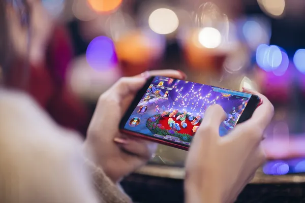 A young woman relaxing with her phone while dynamic casino elements float around her, illustrating the smooth mobile experience offered by the KC666 app.
