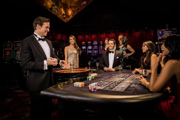 A professional dealer in a tuxedo greeting players at the roulette table, symbolizing the authentic live casino feel at KC666.