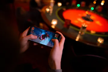 A player using their smartphone during a festive local event, representing KC666’s fully mobile-friendly casino.